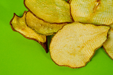 Dried pear chips, closeup shot on a green background. Background for a healthy diet.