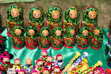 Bright souvenir traditional Matryoshka dolls of handmade stand together on the table with other wooden toys.