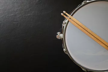 Fotobehang Drum stick and drum on black table background, top view, music concept © tatomm