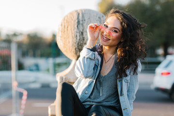 portrait of a young and beautiful Asian woman with sunglasses, looking into the camera on a sunset in the city