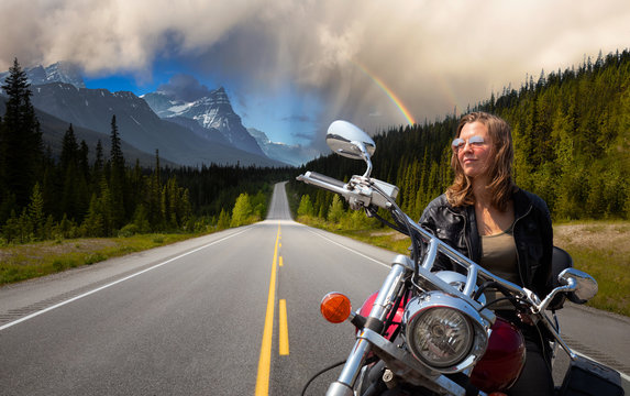 Caucasian Biker Woman on a Motorcycle on a scenic Road in the Canadian Rockies. Image Composite. Background from Banff, Alberta, Canada.