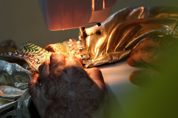 Indian Woman working on a saree on a sewing maching.