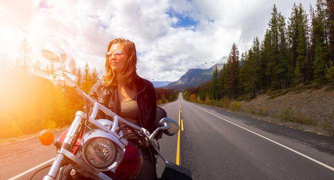 Caucasian Biker Woman on a Motorcycle on a scenic Road in the Canadian Rockies. Image Composite. Background from Banff, Alberta, Canada.