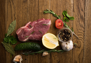 Raw juicy meat steaks ready for roasting on a wooden background