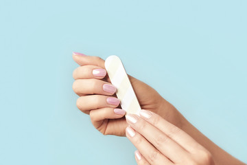 Close up photo of woman doing manicure with nail file.