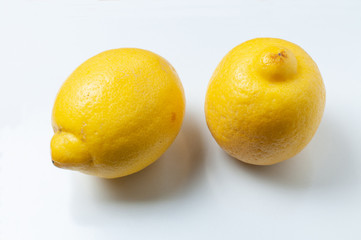 two yellow lemons lying on white background