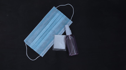 medical mask, antiseptic, disposable gloves on a dark wooden background