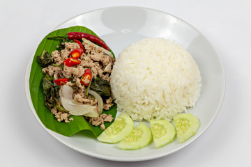 Thai food, fried rice basil pig. Fried minced pork with steam jasmine rice on white plate. delicious Fried minced pork on Banana tree leaves.