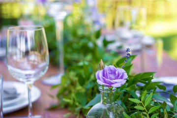 Beautifully decorated wooden table in a summer open-air cafe. Green branch and fresh flowers table decoration