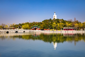 Fototapeta na wymiar The white tower in Beihai Park, Beijing, China. Stone bridge and lake water in Beihai Park.