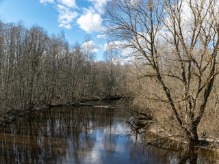 river view from the bridge, small river in early spring, blue sky and reflections in the water