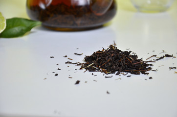 Transparent teapot with black tea, dry tea brewing on the table, bergamot slices, or lemon or lime...