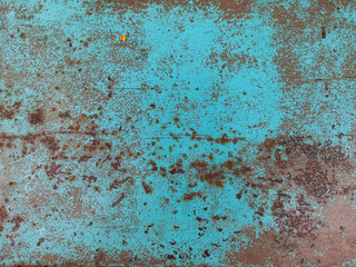 The surface is marred by years of wear and tear, with patches of rust dotting the faded blue paint.