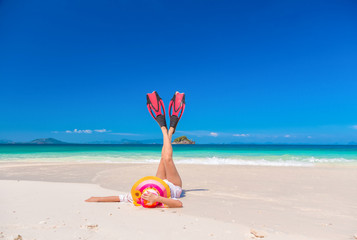 The women enjoy the sea by laying down on sand of beach wearing millinery hat and flipper Both legs up in the air. White sand and crystal sea of tropical beach. Khai island Phuket Thailand