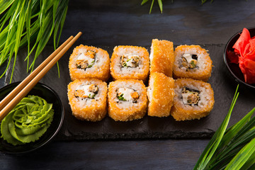 Set of fried sushi rolls with wasabi and ginger on a black background. Japanese oriental cuisine