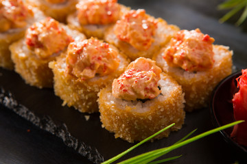 Set of baked sushi rolls with wasabi and ginger on a black background. Japanese oriental cuisine