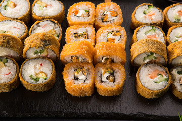 Set of fried sushi rolls with wasabi and ginger on a black background. Japanese oriental cuisine