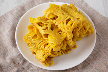 Homemade Net Crepe Roti Jala on a white plate on a white wooden background, low angle view. Close-up.