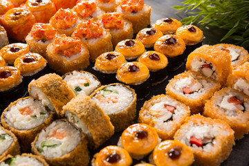 Set of baked sushi rolls with wasabi and ginger on a black background. Japanese oriental cuisine