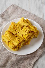 Homemade Net Crepe Roti Jala on a white plate, side view.