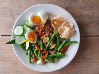 Gado gado dish on wooden table with vegetables egg and satay sauce in perspective