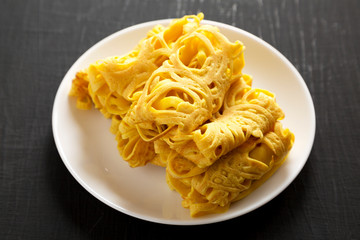 Homemade Net Crepe Roti Jala on a white plate on a black surface, low angle view. Space for text.