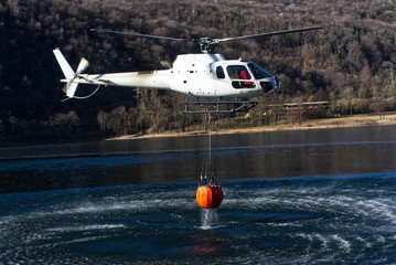 helikopter bekämpft einen Waldbrand mit wasser vom see © G_T_K_