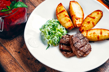 A white plate with rustic potato medallions and coleslaw