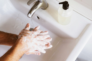 Man cleaning his hands using liquid disinfectant soap and water.