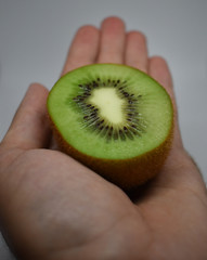 Hand holding a green kiwi cut in half