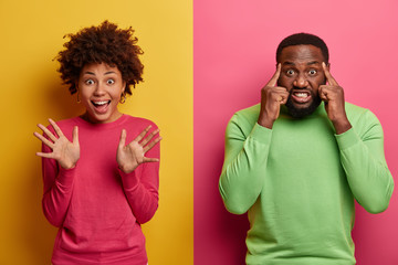 Happy joyful woman raises palms, waves hands in hi, makes friendly gesture, intense bearded man...