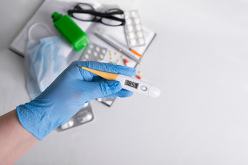 medicines along with a thermometer are on the table, flat lay. vitamins, nutritional supplements, insulin syringe, doctor's glasses. thermometer with high temperature. medical mask with an antiseptic