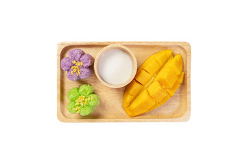 Mango fruit, sweet sticky rice cooked with pandan leave or butterfly pea flower and fried soy and coconut juice in wooden plate on isolated white background. Thai popular dessert on summer. Top view.