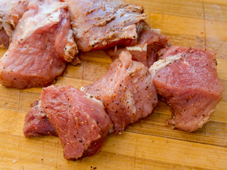 Pieces of pickled raw pork meat on a wooden board.