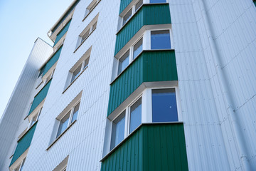 facade of a new multi-storey building with white and green metal siding, many Windows