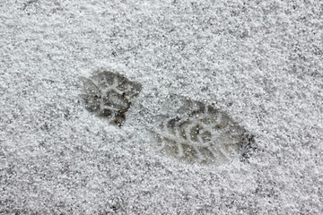 footprints of a man in the fresh snow. Changeable weather due to global warming, in the spring after the rain fell hail
