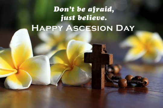 Do not be afraid, just believe. Happy and blessed ascension day of Jesus Christ concept with faithful message, wooden holy cross crucifix, rosary beads the Catholic symbol and Bali frangipani flowers.