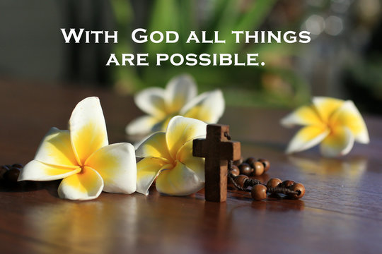 Christian inspirational motivational quote - With God all things are possible. With wooden rosary beads the Catholic symbol, Jesus Christ holy cross crucifix and Bali frangipani flowers background. 