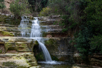 Fototapeta na wymiar Beautiful waterfall splashing in the canyon creating a small lake