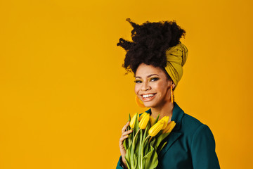 Profile portrait of a smiling young woman with big yellow earrings, afro hair wrapped with head...