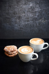 Two cups of cappuccino with cookies