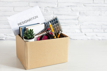 Cardboard box with office suplies on the desk. Dismissal of employment and resignation concept.