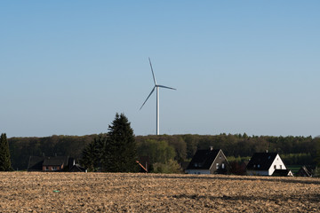 Wind turbine in rural area with residential buildings in the foreground