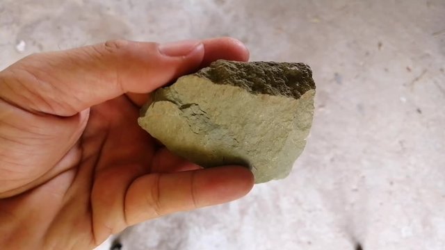 Shale stone in a hand. Shale is a fine-grained sedimentary rock generated from the compaction of silt and clay-size mineral particles.