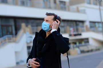 People with face mask. Concept with copy space. Portrait of adult man in quarantine of flu. Photo on the street in the city