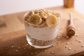 Yogurt with oats, banana and honey on wooden table. Healthy and nutritious snack.