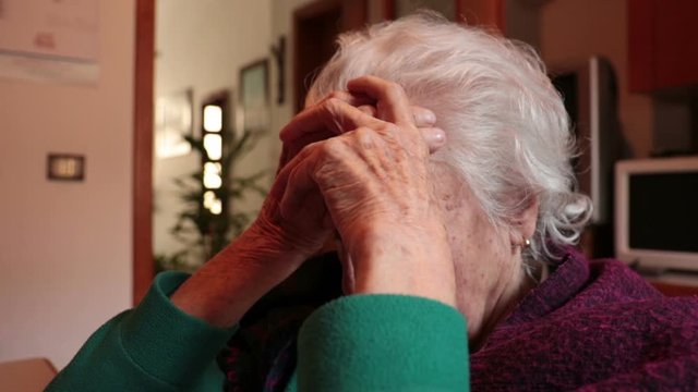 Lonely old woman at home. Very old lady covering her face with wrinkled hands
