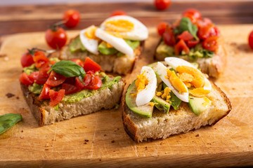 Mixed avocado toast with boiled eggs and tomatoes. Ideas for fast and nutritious dish. Summer food.