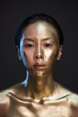 Portrait of young asian woman in golden paint