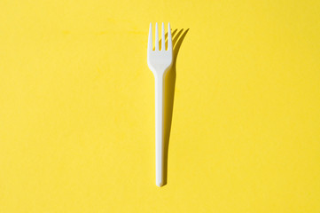 White plastic fork on a yellow background
